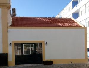 a white building with a black door and a red roof at Fisherman's Inn Loft in Montijo