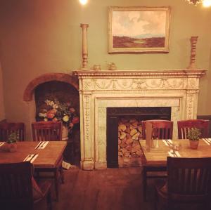 a fireplace in a dining room with tables and chairs at Galtres Lodge Hotel & Forest Restaurant in York