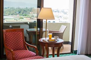 a table with a coffee cup and a chair with a lamp at Barceló Guatemala City in Guatemala