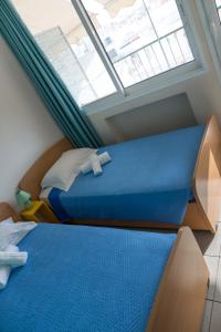 2 camas en una habitación con ventana en Welcommon Hostel en Atenas