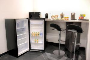 an open refrigerator next to a counter with two stools at B&B AIRPORT BARI DELUXE28 in Bari