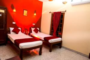 two beds in a room with red walls at Ram Guest House in Pondicherry