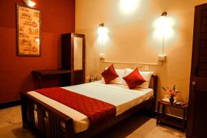 um quarto com uma cama com lençóis vermelhos e almofadas vermelhas em Ram Guest House em Pondicherry