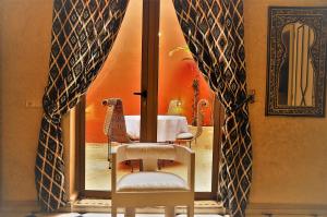 una sedia in una stanza con tavolo e finestra di Riad l'Escale de Marrakech a Marrakech