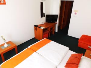 a bedroom with a bed and a desk and a television at Penzión Helios in Bratislava