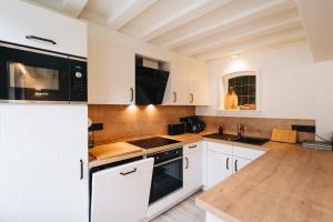 a kitchen with white cabinets and black appliances at Holiday House BURGBLICK2 with garden - VOSPROPERTIES in Monschau