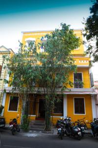 um grupo de motociclos estacionados em frente a um edifício amarelo em Ram Guest House em Pondicherry