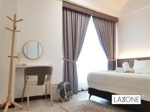 a bedroom with a bed and a desk and a mirror at Sutera Avenue Kota Kinabalu - Laxzone Suite in Kampong Sembulan