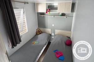 a small bedroom with two beds and a window at Camping Le Roussillon - Maeva in Saint-Cyprien +9 photos