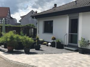 a white house with potted plants in front of it at Ferienwohnung Lippert in Künzell