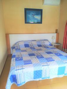 a bedroom with a bed with a blue and white quilt at Posada Chloe Santiago in Santiago de la Ribera