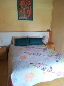 a bedroom with a bed with a colorful bedspread at Posada Chloe Santiago in Santiago de la Ribera