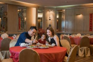 a family eating food at a table in a restaurant at Berjaya Tioman Resort in Tioman Island