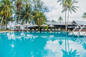 a swimming pool with palm trees and umbrellas at Berjaya Tioman Resort in Tioman Island