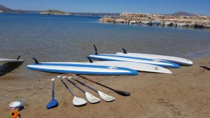 four surfboards and paddles are lined up on the beach at 7 Olives Apartments in Almyrida