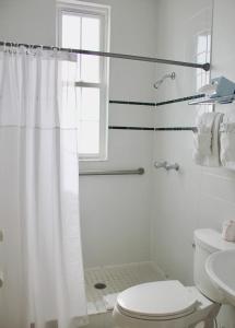 a white bathroom with a shower and a toilet at Casa Marina Hotel & Restaurant - Jacksonville Beach in Jacksonville Beach