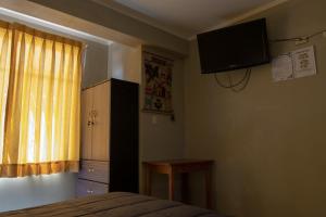 1 dormitorio con 1 cama y TV en la pared en Hostal Roma, en Ayacucho
