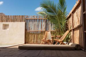a patio with two chairs and a palm tree at LaIsla Holbox Villa in Holbox Island