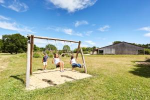 two girls and a boy sitting on a swing at Domaine de l'Oiselière in Chauché