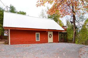 a red cabin with a white door and a tree at Lover's Loft in Gatlinburg