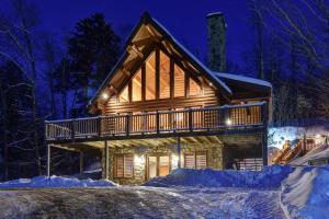 una cabaña de madera en la nieve por la noche en Chic Familiale, Relaxant avec spa en montagnes en Labelle