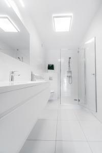 a white bathroom with two sinks and a shower at Marittimo Resort in Świnoujście