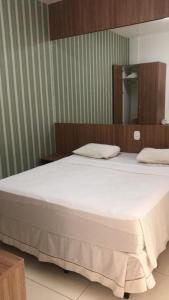 a bedroom with a large white bed with a mirror at Resort Encontro das Águas in Caldas Novas