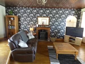 a living room with a leather couch and a tv at St Clair House in Orkney