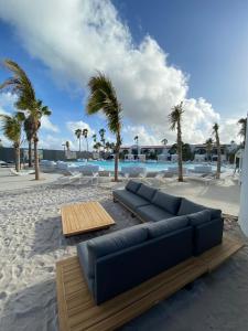 eine blaue Couch am Strand mit Palmen in der Unterkunft Van der Valk Plaza Beach & Dive Resort Bonaire in Kralendijk