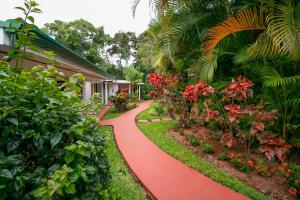 a red path in front of a house with flowers at Hotel La Rosa de America in Alajuela