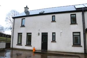 une maison blanche avec une porte noire et une bouche d'incendie dans l'établissement Emy Lake Apartment - near Castle Leslie, Glaslough, à Monaghan