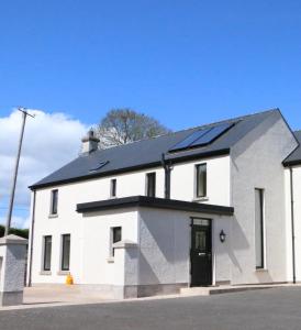 a white house with solar panels on the roof at Emy Lake Apartment - near Castle Leslie, Glaslough in Monaghan