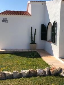 een wit huis met een cactus en twee ramen bij BiniBridge in Binibeca