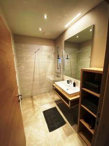a bathroom with a sink and a shower and a mirror at Wellness-Pension Jagahütt'n in Schladming