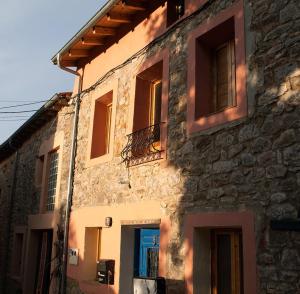 ein Steingebäude mit Fenstern und einem Balkon in der Unterkunft Albergue el Hacedor in La Aldea del Portillo de Busto