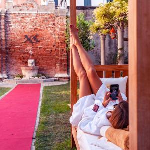 
a woman laying on a bed in front of a building at Excess Venice Boutique Hotel & Private Spa - Adults Only in Venice
