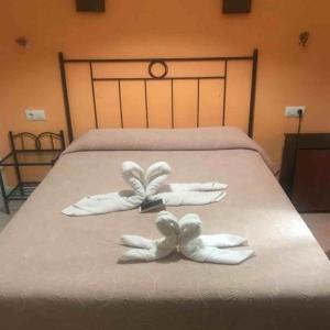 two white towels on a bed in a room at Hostal Malia in Conil de la Frontera