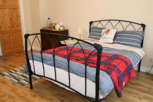 a bedroom with a black bed with a red and blue blanket at Emy Lake Studio in Monaghan