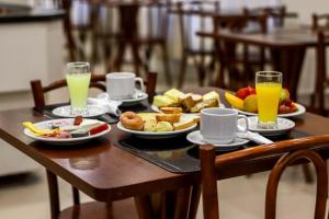 uma mesa com pratos de comida e dois copos de sumo de laranja em Hotel Ryan em Balneário Camboriú