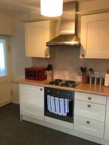 a kitchen with a stove and a microwave at Aelfor Cozy Cottage in Barmouth +13 photos