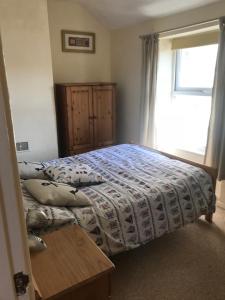 a bedroom with a bed with a comforter and a window at Aelfor Cozy Cottage in Barmouth