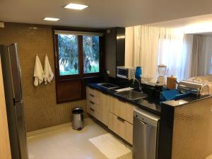 a large kitchen with a sink and a window at Flat 4 Suites Hotel Portal Gravata in Gravatá