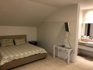um quarto com uma cama, uma televisão e uma mesa em Flat 4 Suites Hotel Portal Gravata em Gravatá