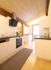 uma cozinha com armários brancos e um tecto de madeira em Berghof Vöglerbrand em Andelsbuch