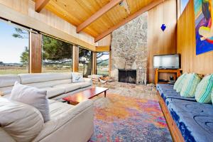 a living room with couches and a stone fireplace at Anam Cara in Sea Ranch