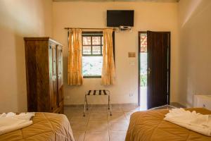 a bedroom with two beds and a television on the wall at Pousada das Cavernas in Iporanga