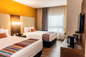 Habitación de hotel con 2 camas y TV en LATAM HOTEL Plaza Pradera Quetzaltenango en Quetzaltenango