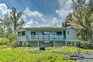 a green house with a balcony in a yard at Direct Oceanfront, Big Island Vacation Rental Home in Keaau