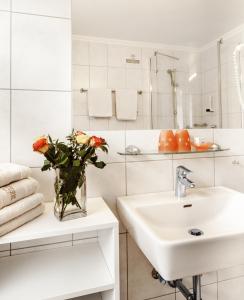 un baño blanco con lavabo y un jarrón de flores en Kraners Alpenhof BIO Bed and Breakfast Pension, en Weissensee