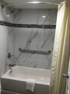 a bathroom with a white tub and a marble shower curtain at Travel Inn & Suites in Humble